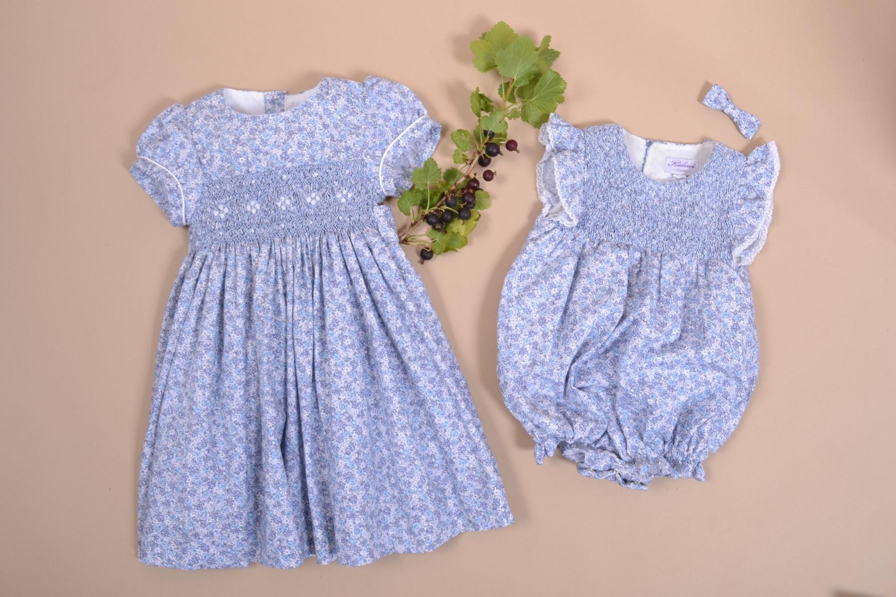 Capucine, Baby girl's romper, round neck, smocked bust, ruffled armhole with lace finish, 3 snaps on the bottom, in small blue flower print