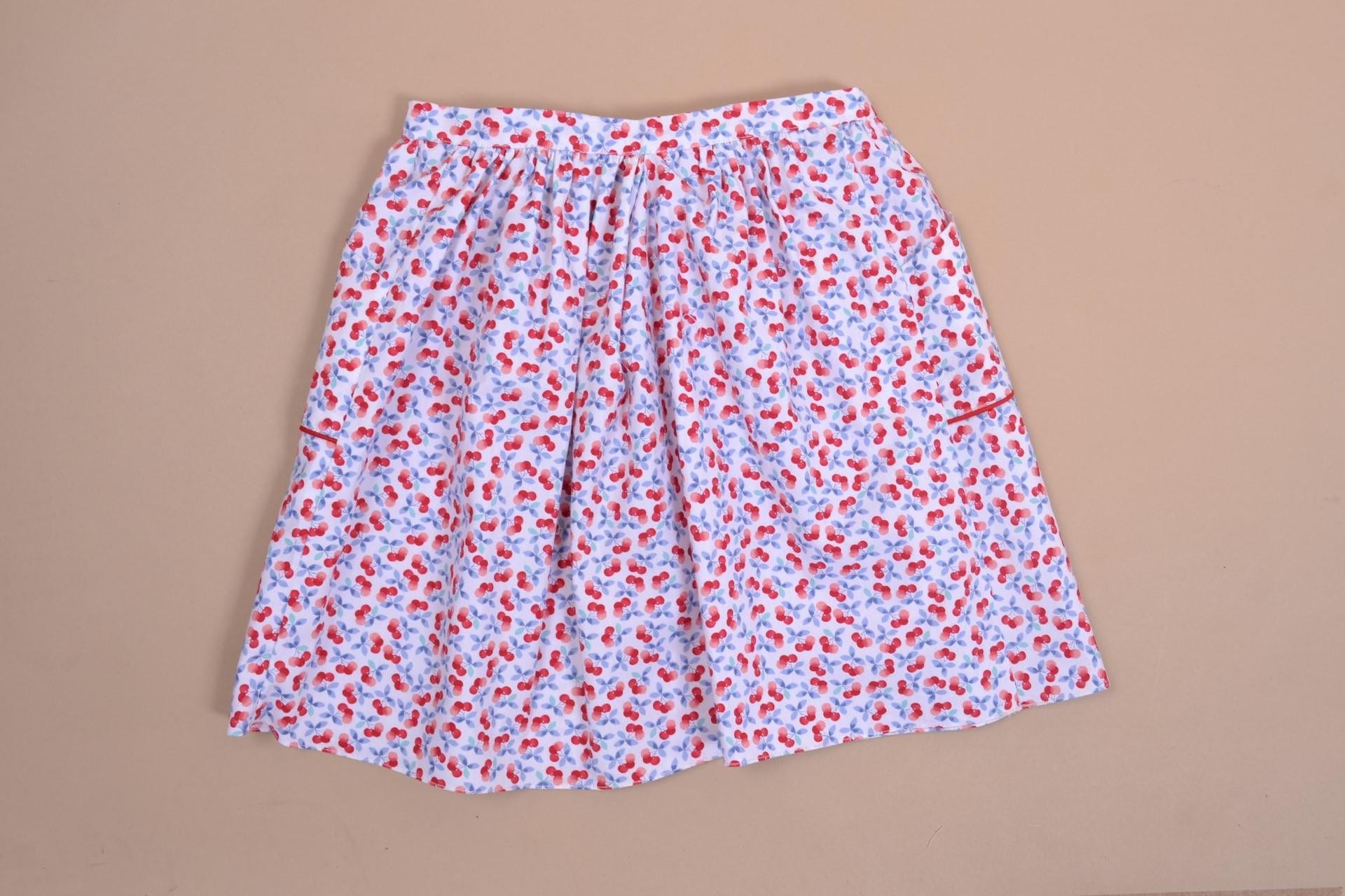 Jasmin, jupe poches passepoilées rouges, ouverte sur le devant, en imprimé cerises bleues et rouges - red piped pocket skirt, open at the front, in blue and red cherry print